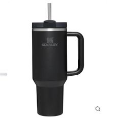 the stanley travel mug is black and has a handle that holds a straw in it