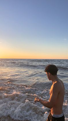 a man standing on top of a sandy beach next to the ocean with waves coming in