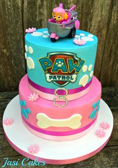 a birthday cake with paw patrol on top and pink, blue, and yellow frosting