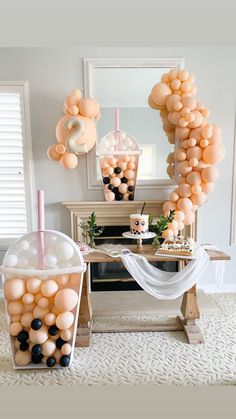 some balloons are hanging in front of a table with drinks and decorations on top of it