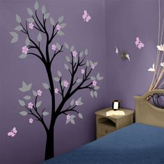 a bedroom decorated in purple and green with butterflies on the tree wall decal above the bed