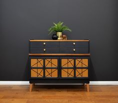 a black and brown dresser with a potted plant on top