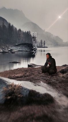 a man sitting on the ground next to a lake