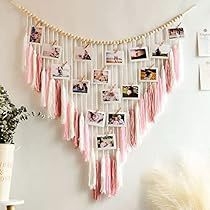 a wall hanging with pictures and tassels on it in a room next to a plant