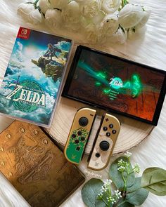 the nintendo zelda game is on display next to other games and accessories, along with some flowers