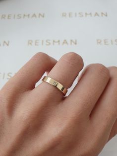 a woman's hand with a gold ring on top of her finger and an inscription in the background