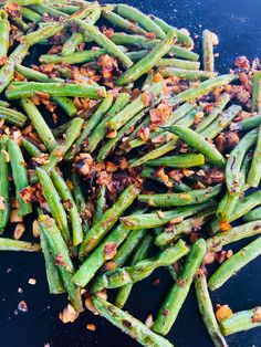 cooked green beans with bacon and seasonings on a black plate, ready to be eaten