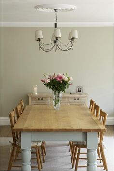 a dining room table with chairs and a vase of flowers on the top of it