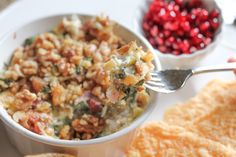 a white bowl filled with food next to crackers and cranberries