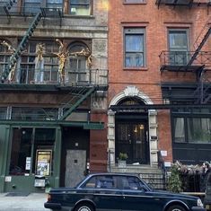 a car parked in front of an apartment building with fire escapes on the second floor