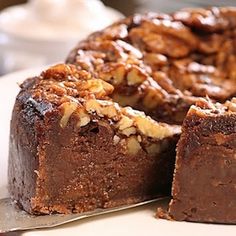 a chocolate cake with walnuts on top and one slice cut out to show the inside