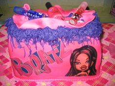 a pink cake with purple icing and various items on it, including lipstick, hair care products