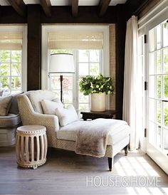 a living room filled with furniture and lots of windows next to a lamp on top of a table