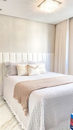 a white bed sitting next to a window in a bedroom