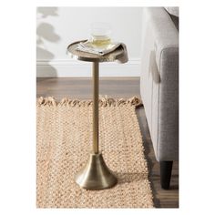 a small table with a glass on it in front of a couch and rugs