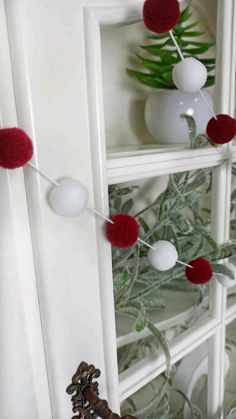 some red and white pom poms are hanging from a shelf in a room