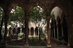 an old building with arches and trees in the courtyard