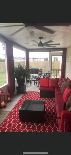 a red couch sitting on top of a red rug next to a table and chairs