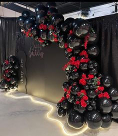 black and red balloons are arranged in the shape of an arch with roses on it