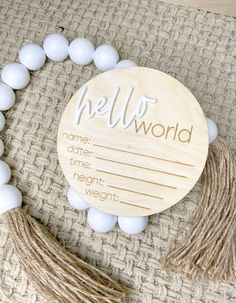 a white beaded bracelet with the word hello world on it and tassels