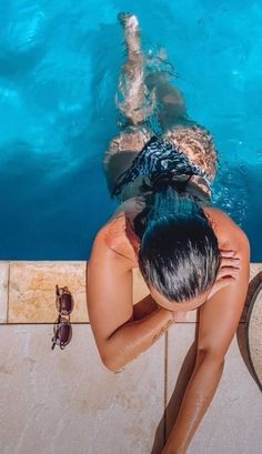 a woman is sitting in the pool looking down