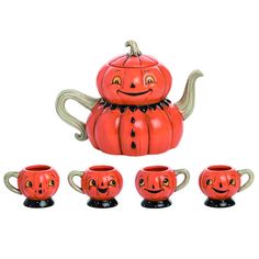 a teapot with four pumpkin faces on it and five mugs in the shape of them