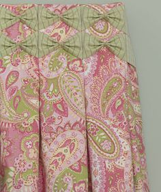 a pink and green skirt with a bow at the waist, on a hanger