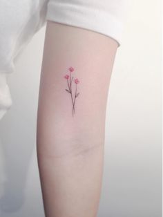 a small pink flower tattoo on the left arm