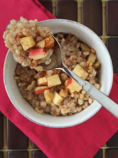 a white bowl filled with oatmeal and apples on top of a red napkin