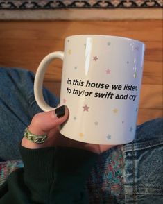 a woman is holding a coffee mug that says in this house we listen to taylor swift and cry