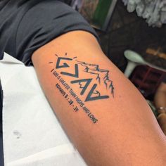 a man with a tattoo on his arm that reads vaz and has mountains in the background