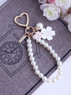 the key chain is attached to a book with flowers on it and a heart charm