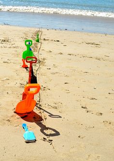 colorful plastic toys are lined up on the beach