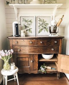 an old wooden dresser with flowers and other items on the top shelf next to it