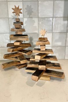 two wooden christmas trees made out of wood planks on a counter top with white tiles behind them