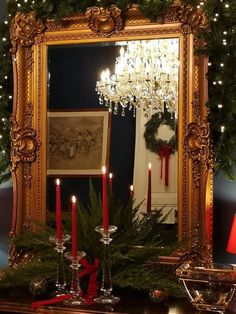 a christmas mantle with candles and wreath on it, in front of a large mirror