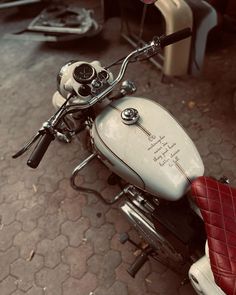 a white motorcycle parked on top of a street next to a red leather seat with writing on it