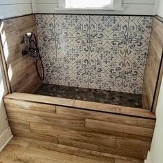 a wooden bench sitting under a window next to a tiled wall and wood flooring