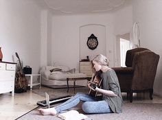 a woman sitting on the floor playing an instrument