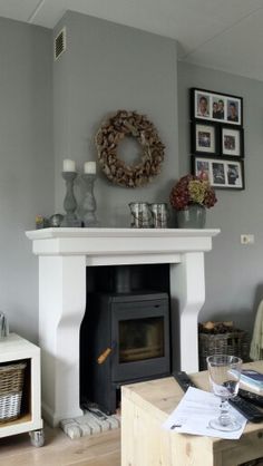 a living room filled with furniture and a fire place in front of a mantle covered in pictures