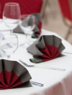 the table is set with red and grey napkins, wine glasses and silverware