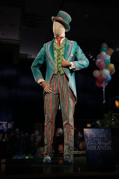 a man's suit and top hat on display in a dark room with balloons