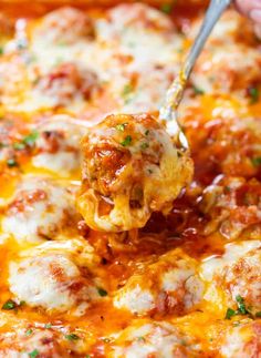 a close up of a person holding a spoon full of cheese covered meatball casserole