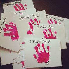 thank you cards with pink handprints on them are arranged on a wooden table