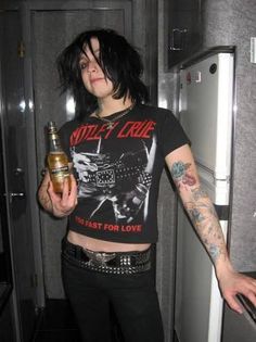 a woman with black hair and tattoos holding a bottle