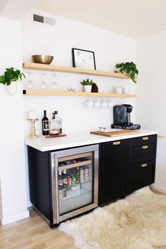 a kitchen with black cabinets and white counter tops, an open refrigerator freezer is in the corner