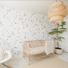 a baby's room with a crib, rocking chair and potted plant