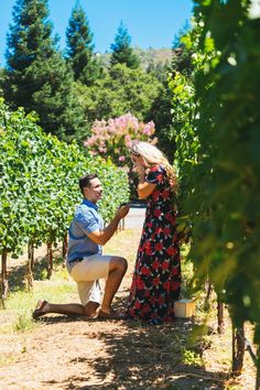 a man kneeling down next to a woman in a field