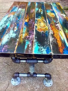 a table made out of metal pipes and painted with colorful paint on the outside wall