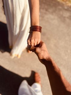 two people holding hands and walking down the street with one person's arm wrapped around the other